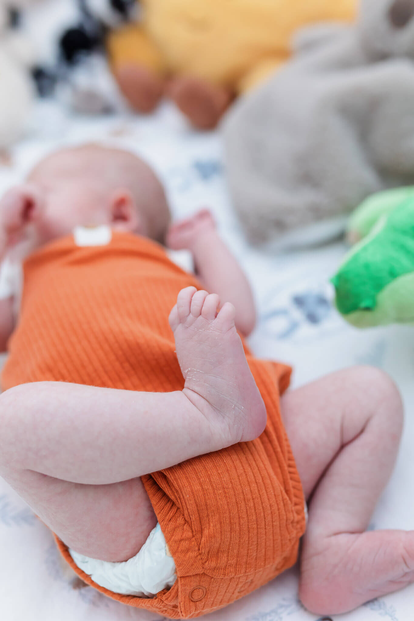 A newborn boy laying in his crib with the focus on his feet.