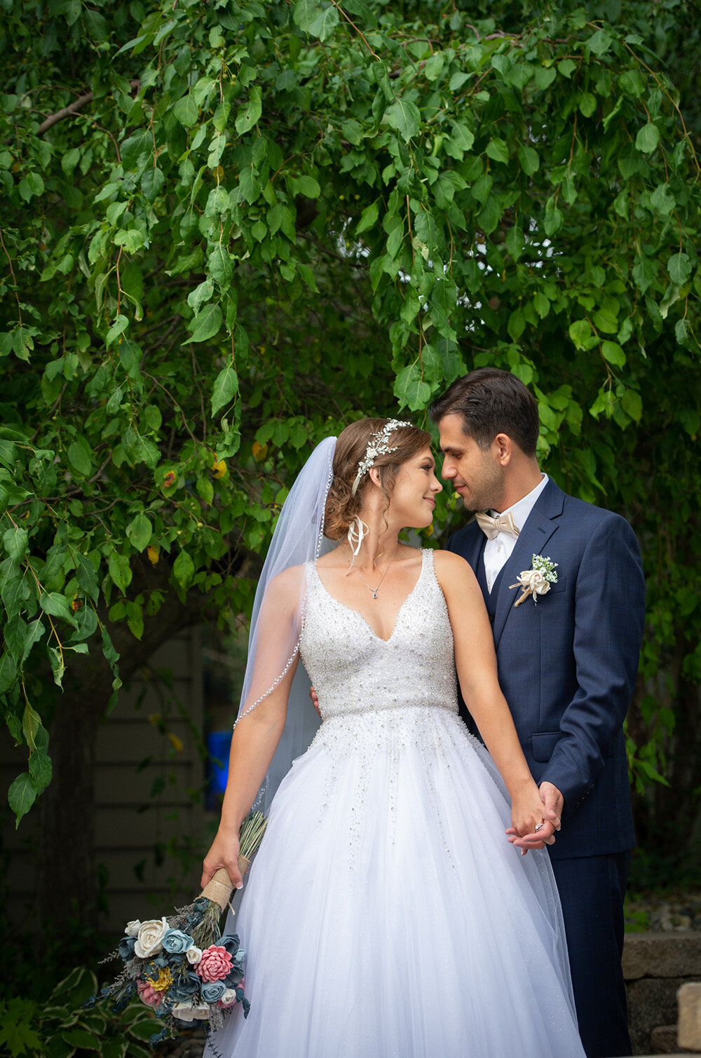 bride and groom hold hands in front of wall with ivy