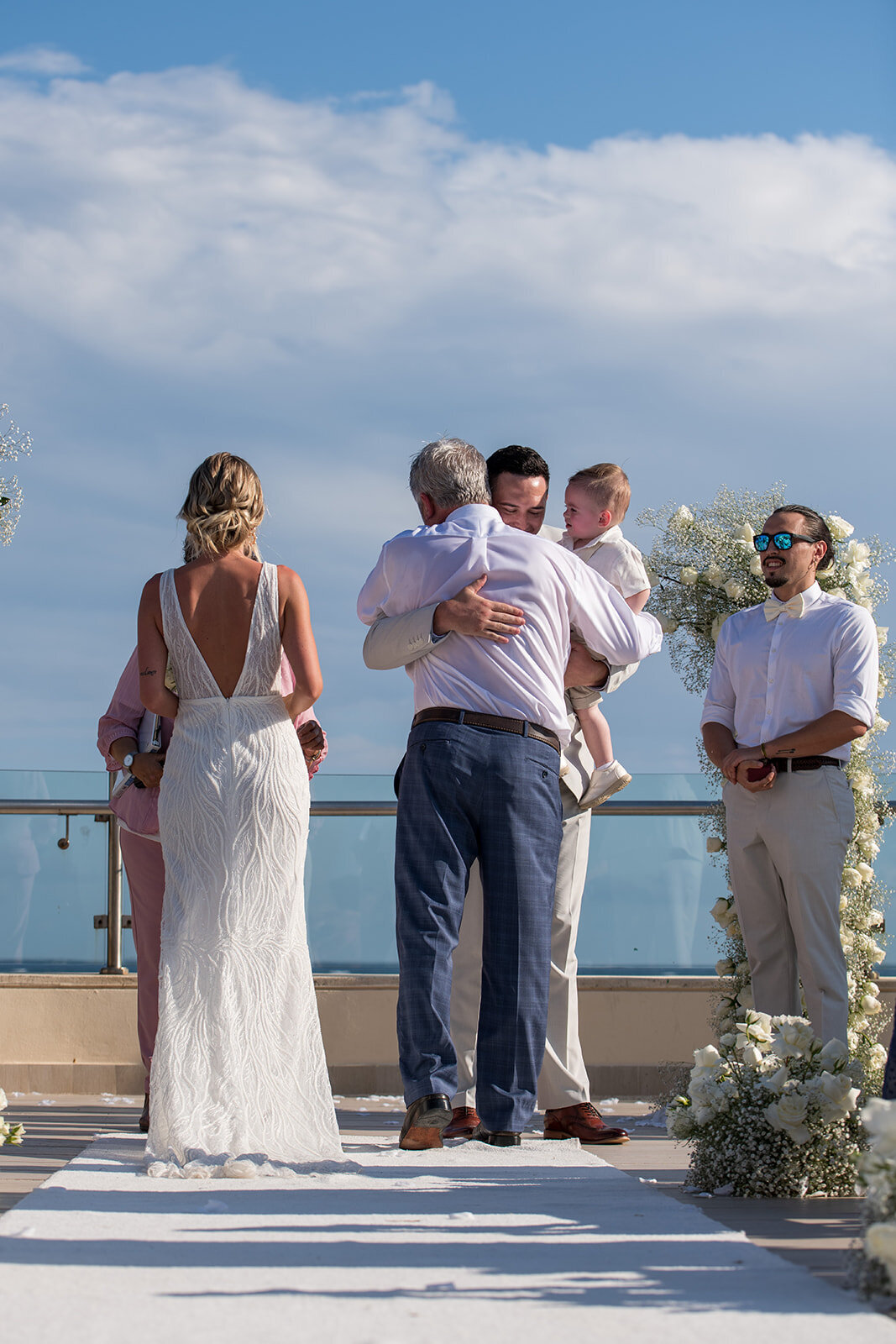 A joyful moment with the bride, groom, and their family celebrating after the wedding ceremony, captured by CMH Studios in a beachside setting.