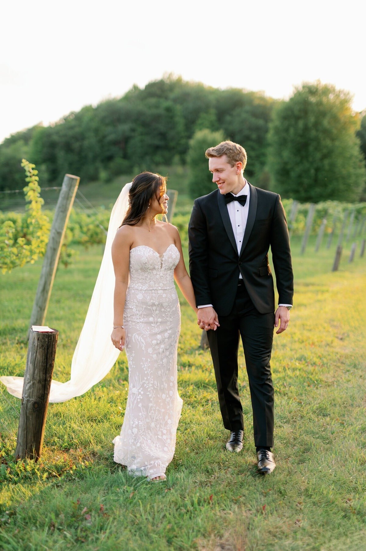bride and groom walk together holding hands outside vineyard at sunset in minneapolis photographed by bauer creative