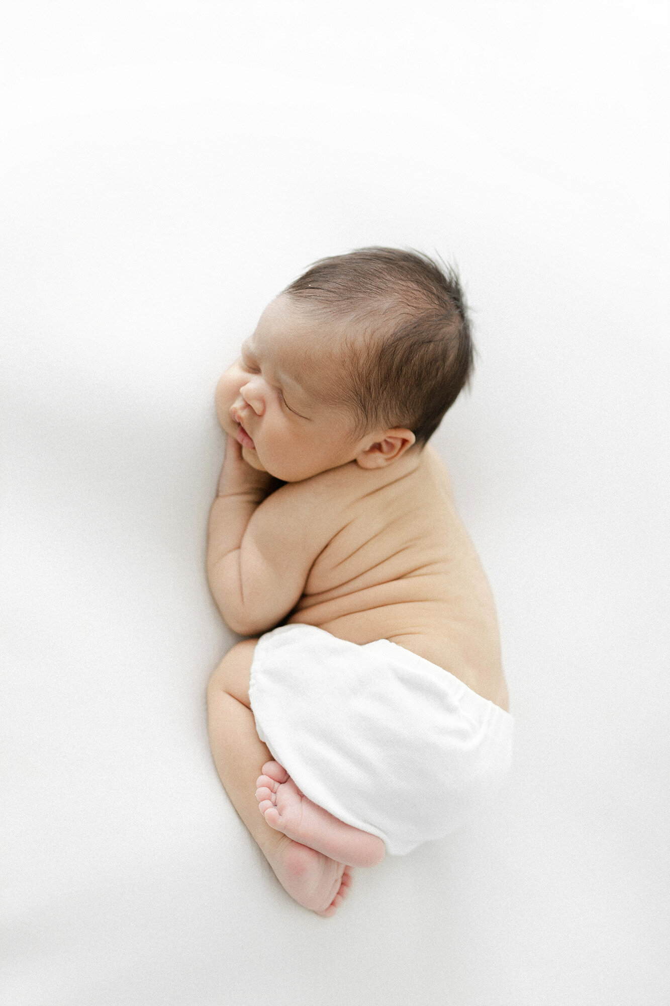 North Dakota newborn photographer | baby boy peacefully sleeping on a white blanket in studio portrait