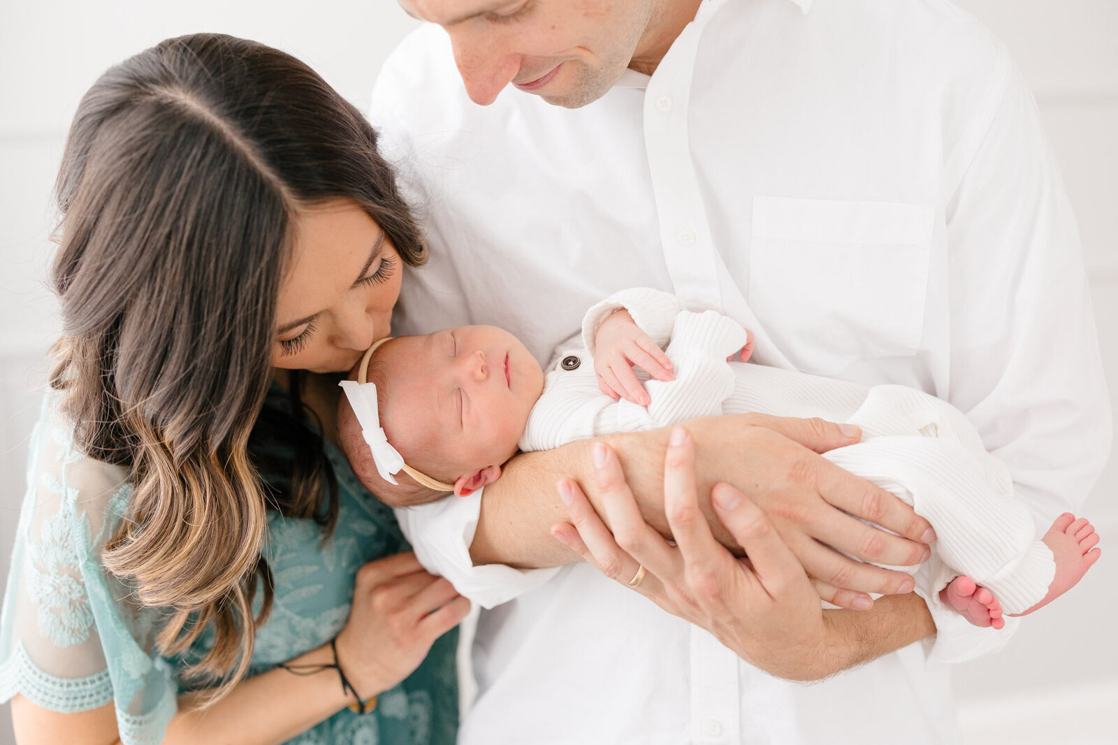 First time mom and dad snuggling their newborn baby girl in a bright northern kentucky photography studio