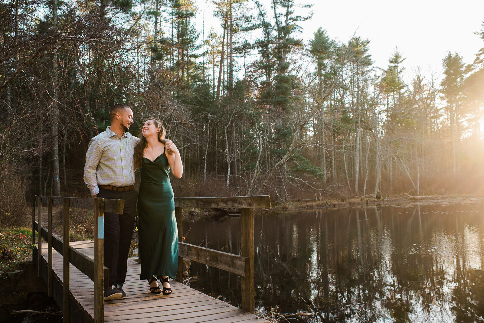 couple walk on dock by water embracing