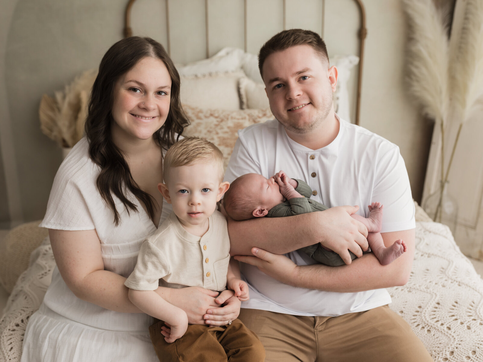 parents holding toddler son and newborn baby boy for studio portraits cleveland newborn photographer