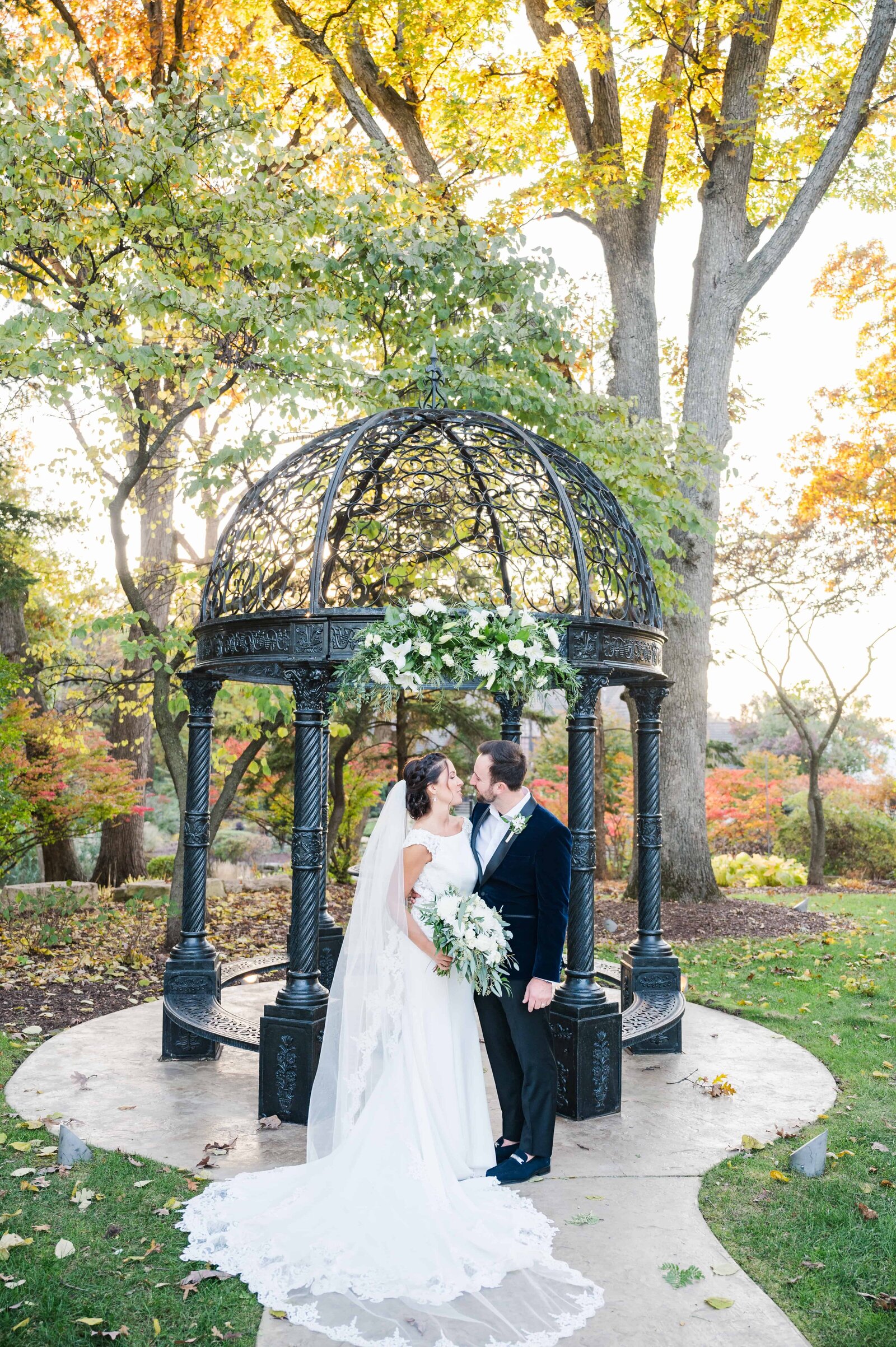 Autumn wedding portrait with bride and groom sharing a kiss .