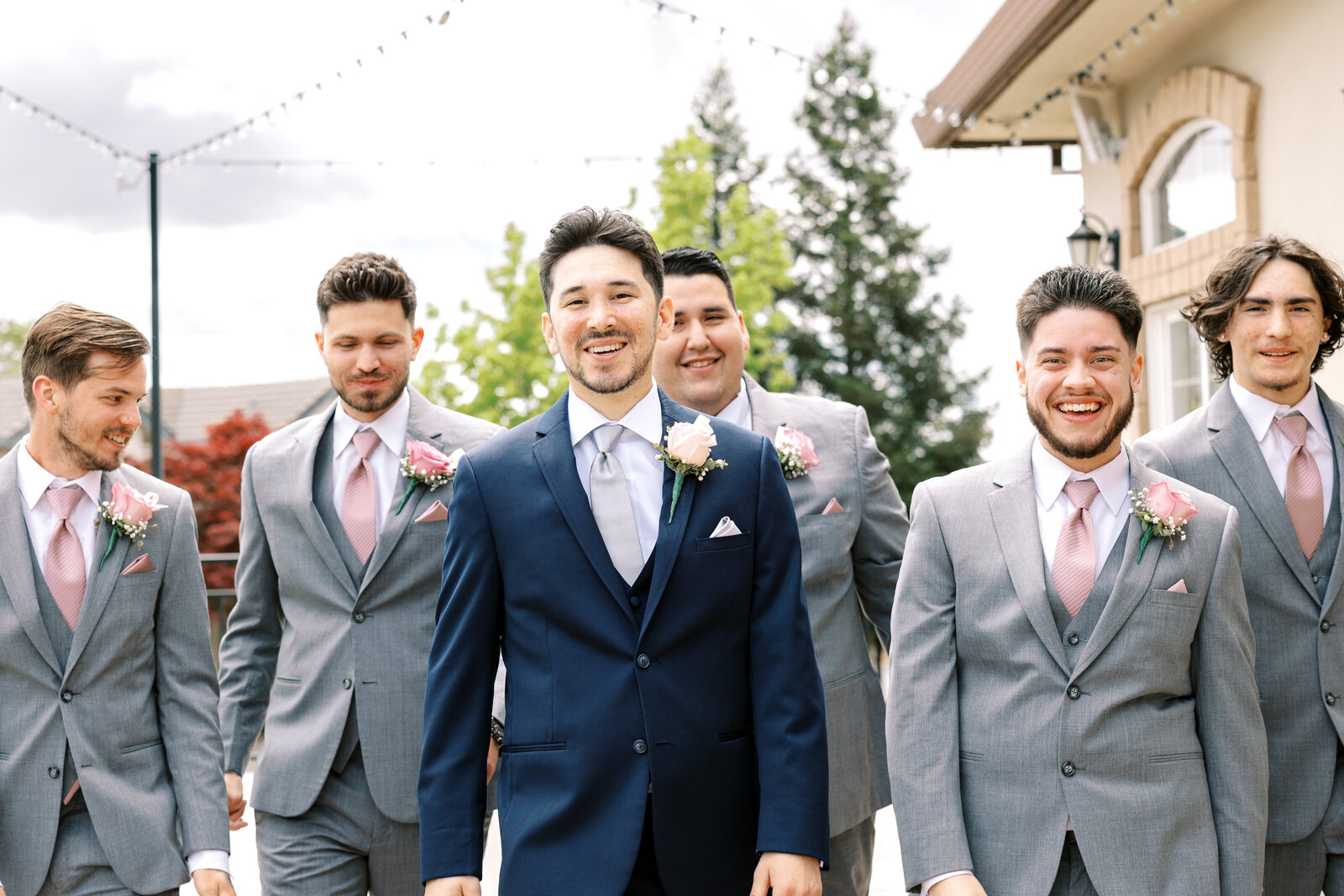 groom in a blue suit walking with his groomsmen outside of his Sacramento wedding venue for wedding pictures captured by sacramento wedding photographer