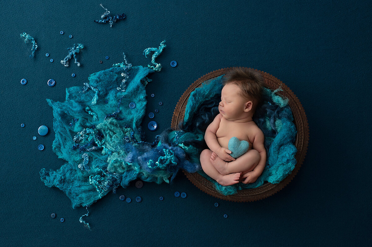 Newborn boy in basket with blue felt, a Dallas newborn photographer.