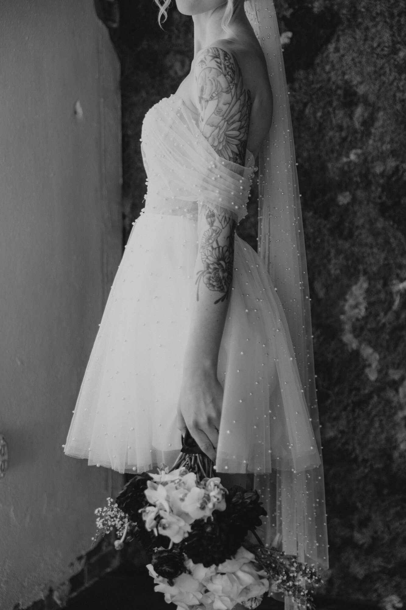 Black and white photo of a bride holding the floral bouquet upside down