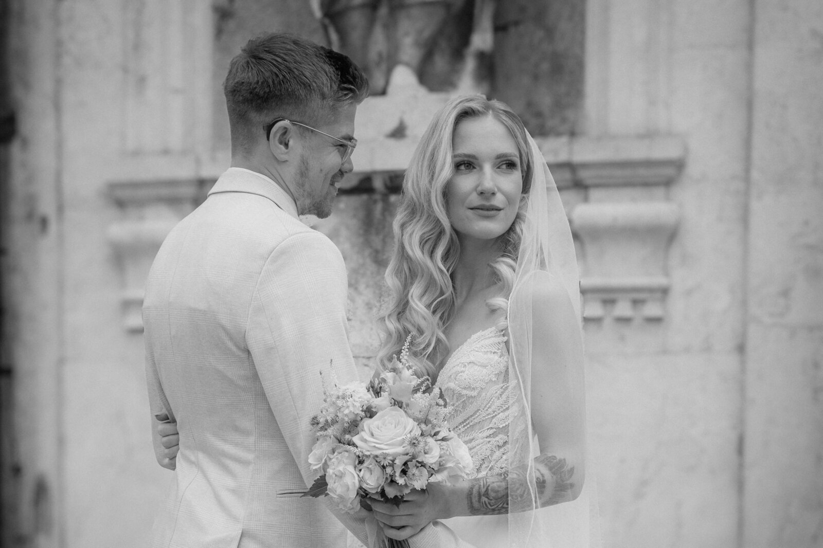 Bride and groom standing close to each other in front of an old building.