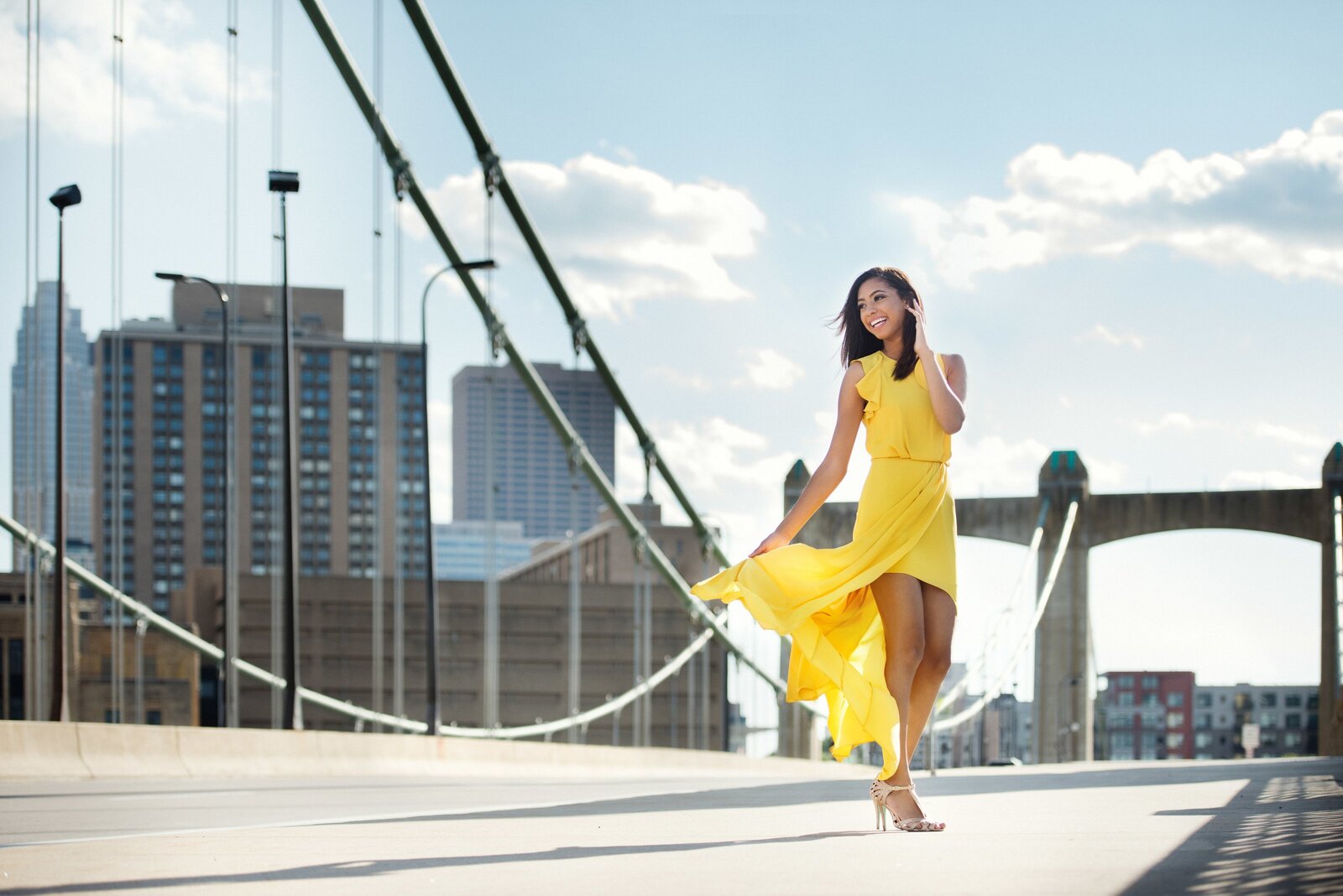 high school senior photo of girl in yellow dress on bridge in minneapolis