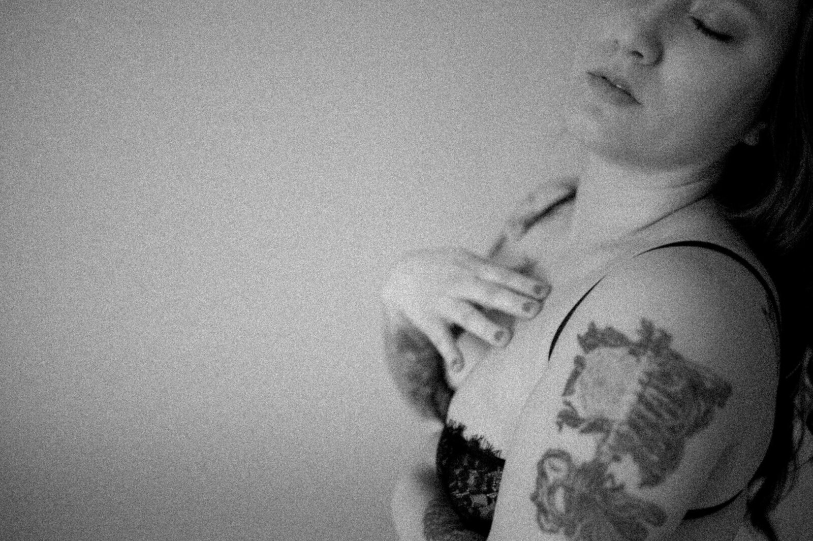 woman in black bra with tattoos and hand on chest