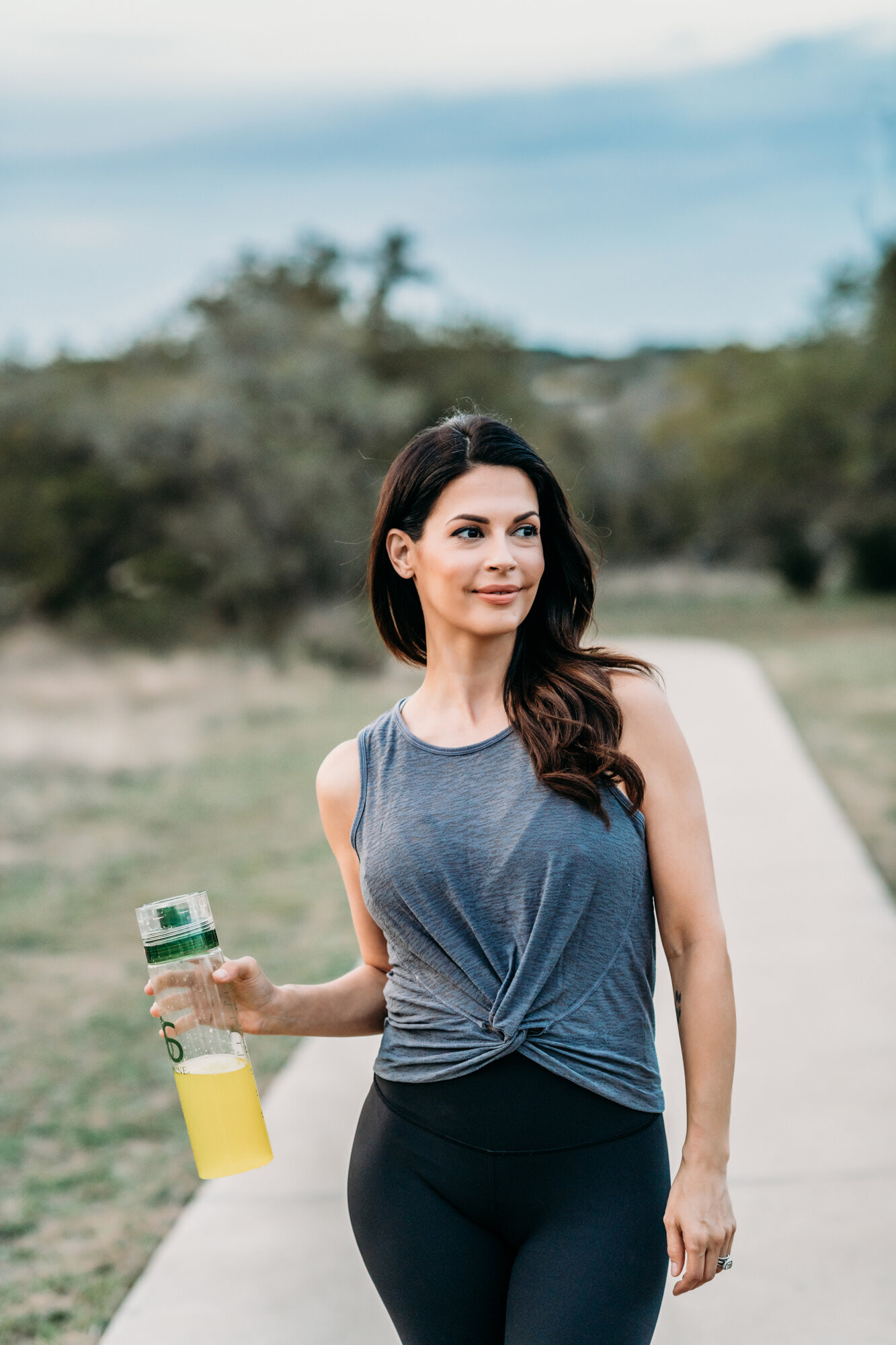 Branding Photographer,  a woman walks on a park trail in fitness apparel with a sport drink