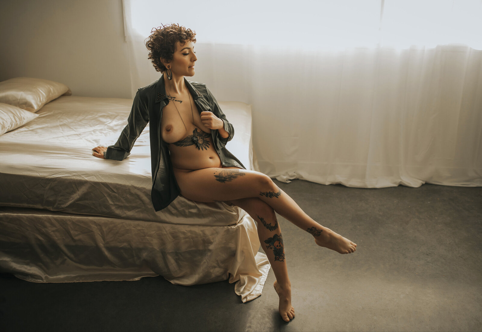 tattooed model posing on bed in boudoir studio