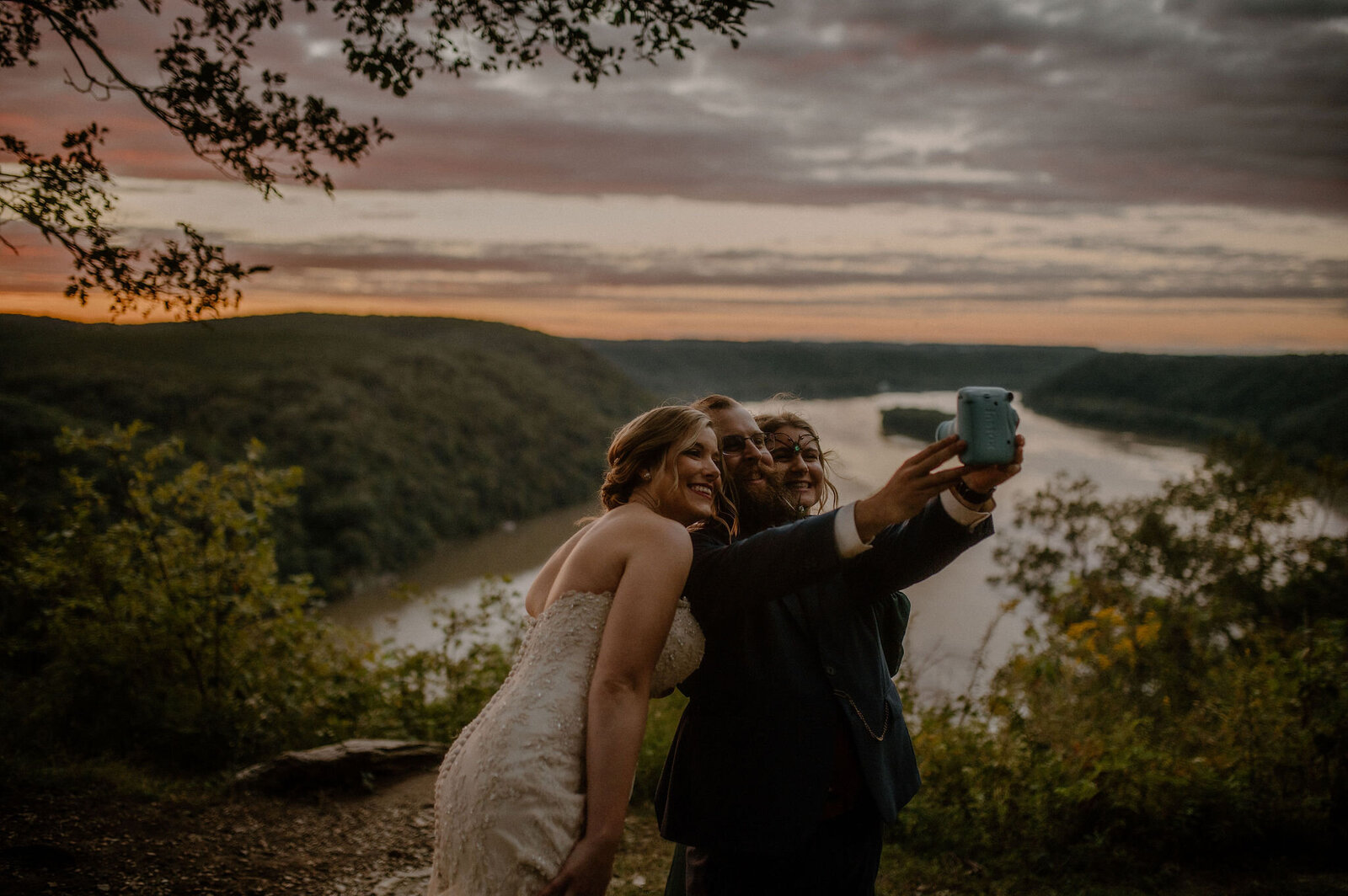 bride and groom taking a selfie at sunset elopement overlooking water