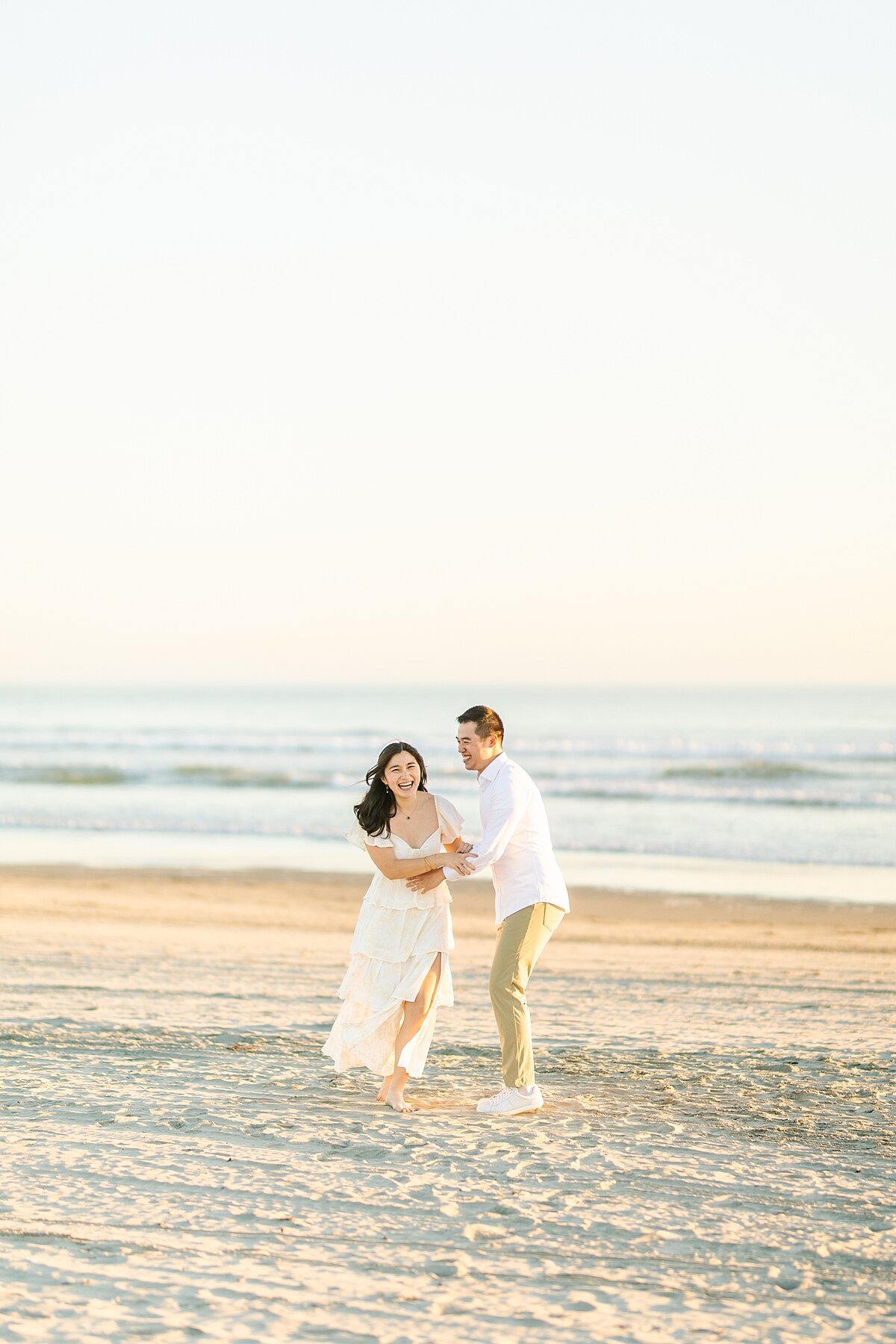 Bride and groom running on the beach together at Coronado Beach in San Diego.