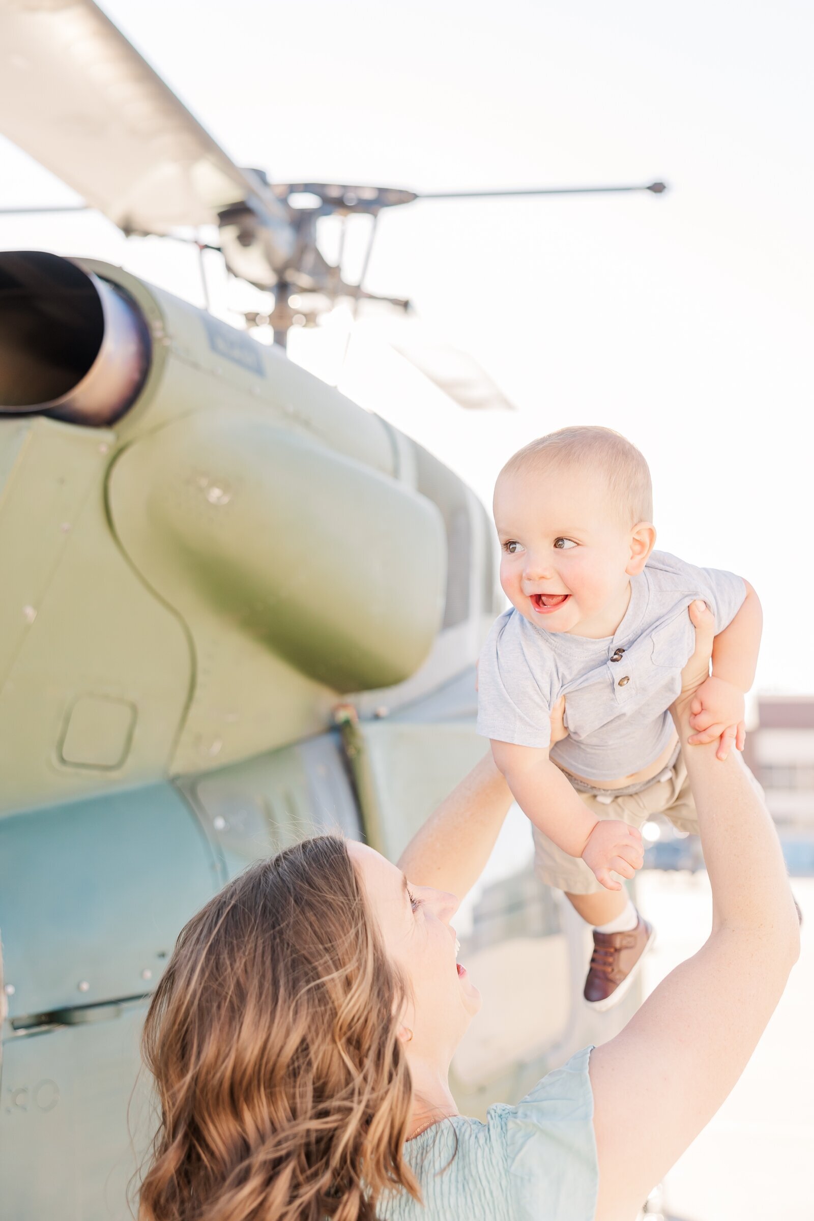 Mom holding her baby in the air in front of an Air Force helicopter