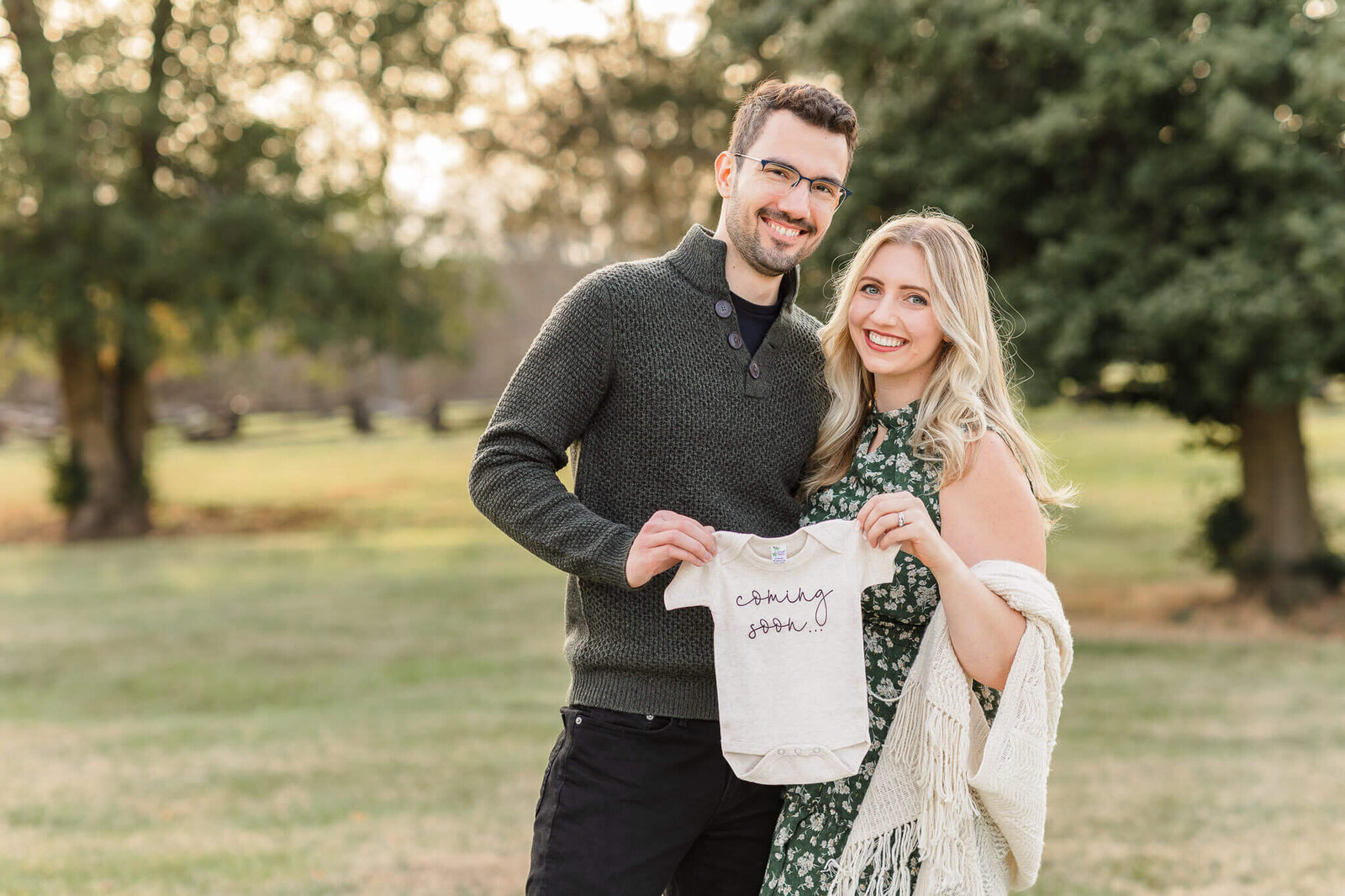 A couple holding a onesie at their Northern Virginia maternity announcement session.