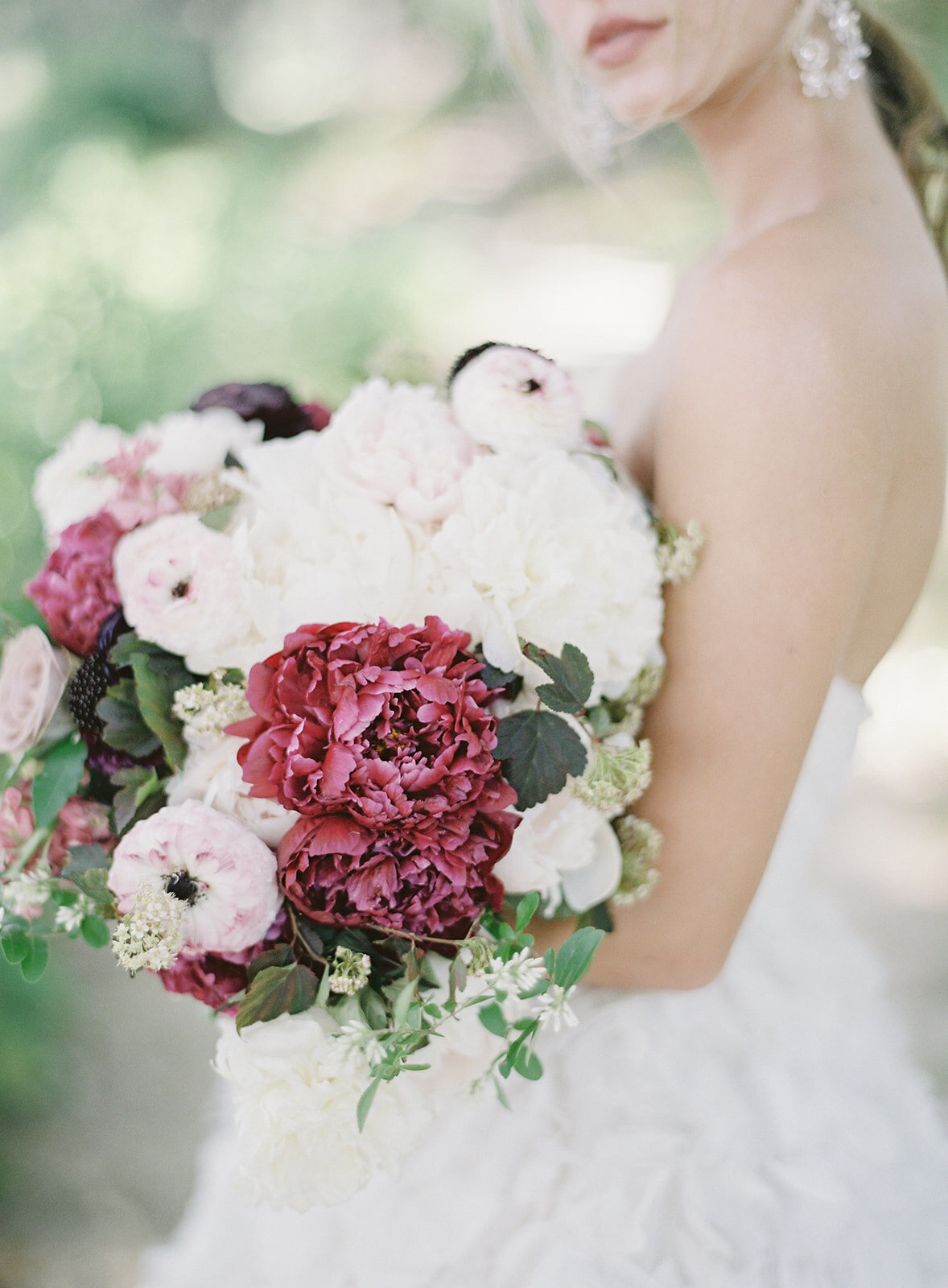 Bride with large floral wedding bouquet in whites, purples and pinks. She is cradling it in her elbow. Photographed by wedding photographers in Charleston Amy Mulder Photography