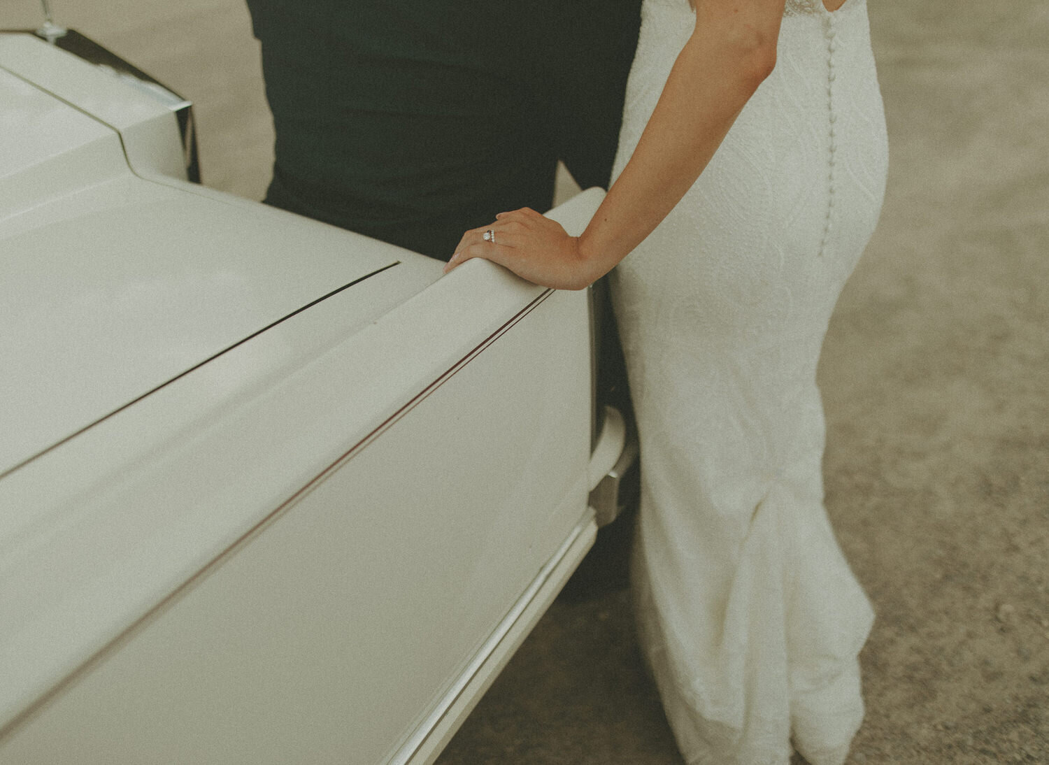 bride and groom leaning against vintage car