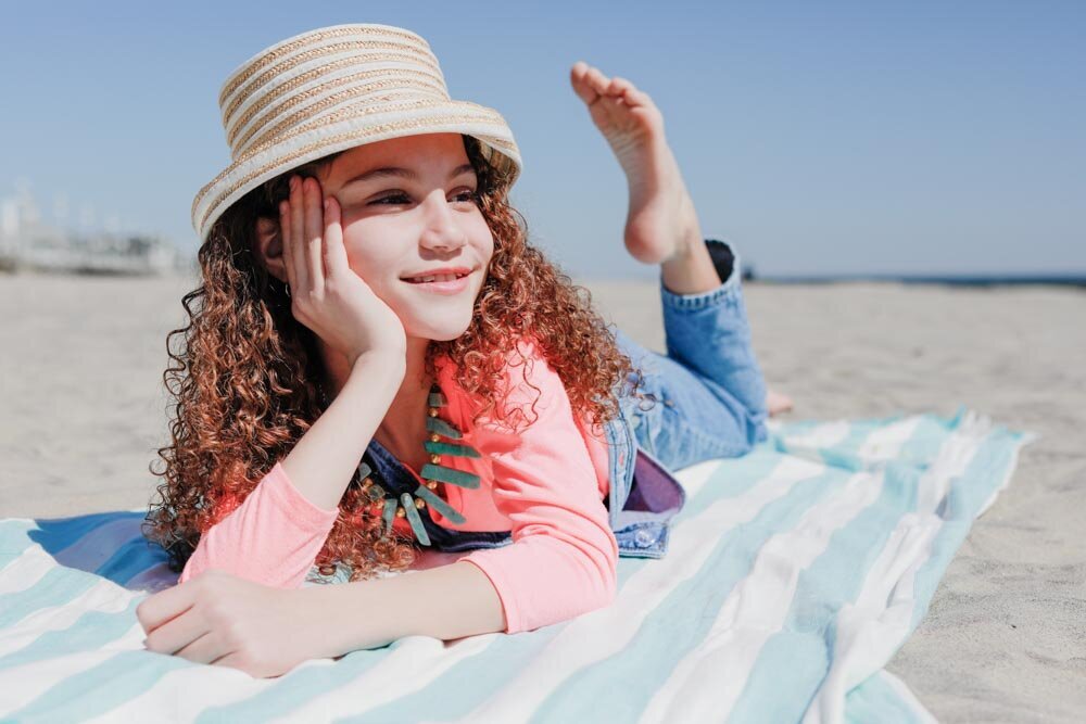 Young kid laying on a beach towel by the ocean