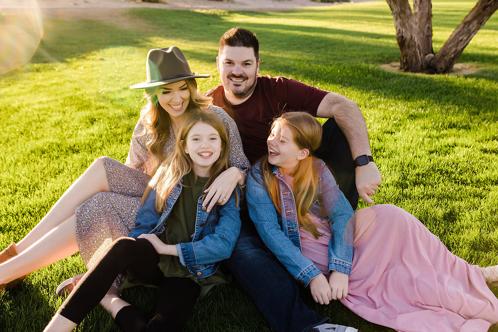 Family photo with a mom, dad, and two daughters on a grassy field