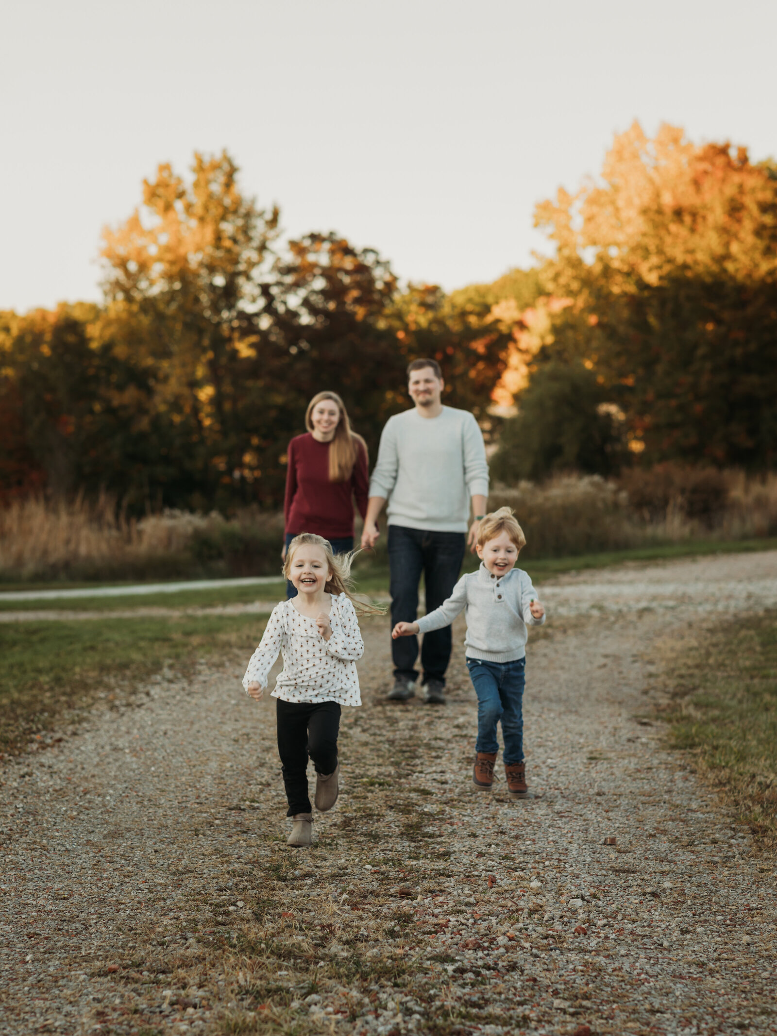 kids running from mom and dad for family photos at park 