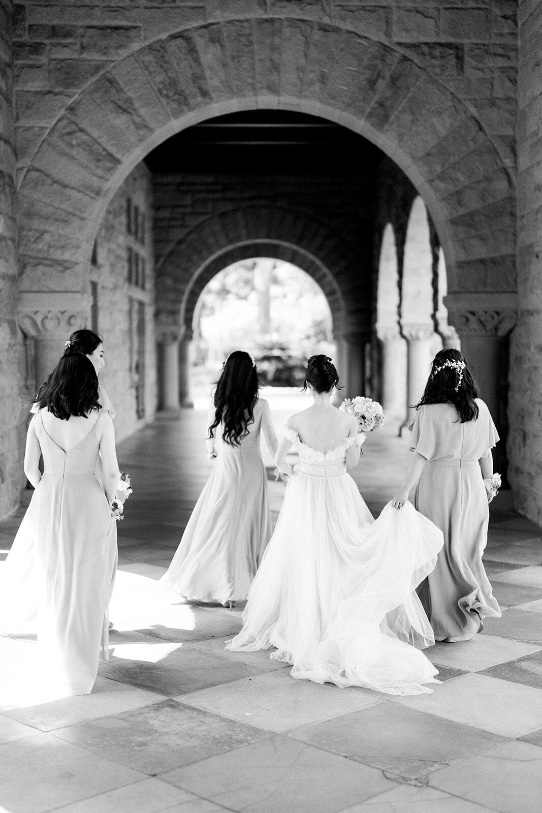 The bride and her bridesmaids celebrate together in the picturesque setting of Stanford University during a beautiful California wedding.