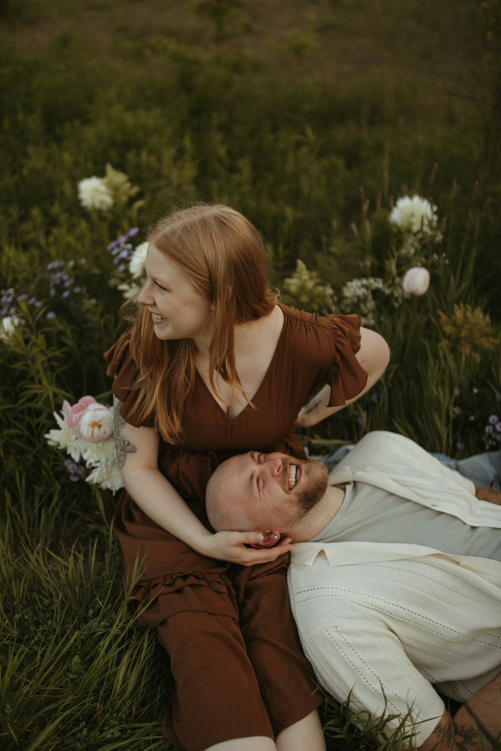couple laughs candidly amongst flowers in southern maine