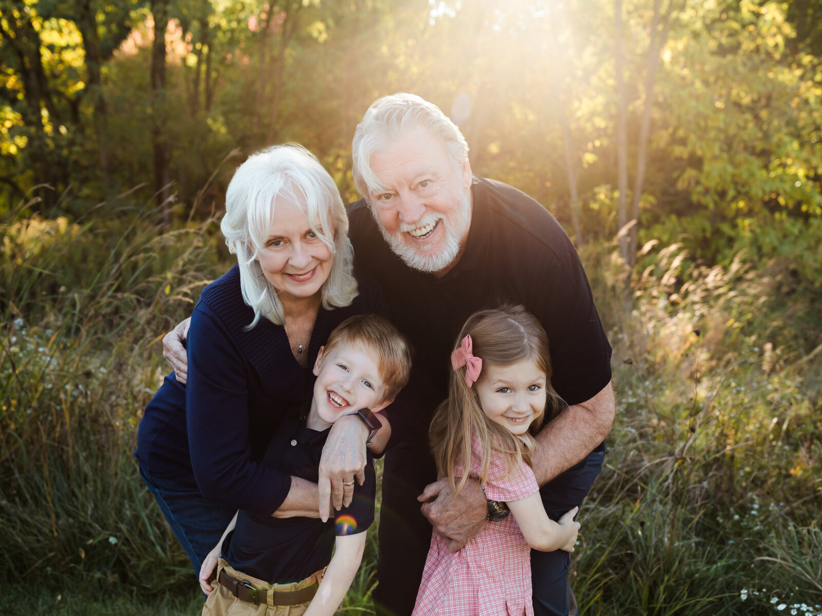 Grandparents and two grandchildren hugging and smiling for family photos at park in parma, ohio