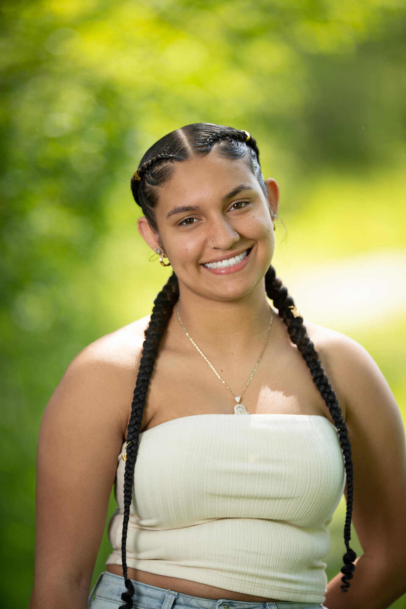 High school senior portrait photography in Clinton MA  of female in a white top smiling at the camera with a green and yellow background stqandign with one hand behind her back