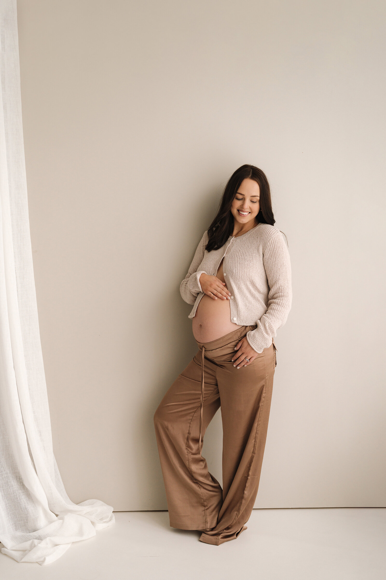pregnant woman stands on beach at sunset during maternity photoshoot