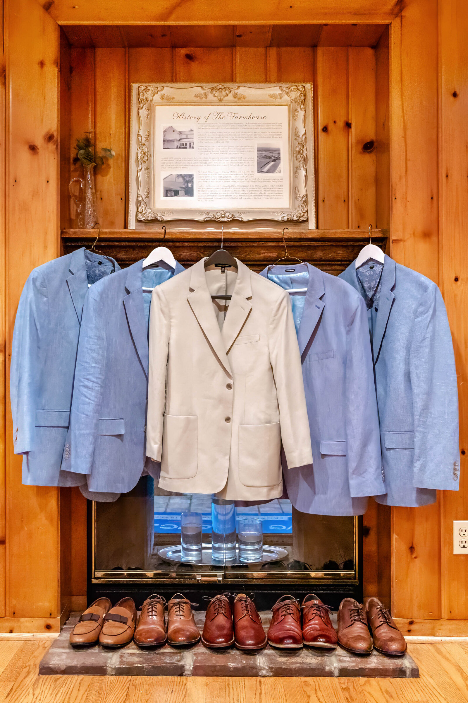 A display of groomsmen’s suits in shades of blue and tan with polished shoes, arranged in a rustic venue in Boone, NC, blending classic style and rustic charm.