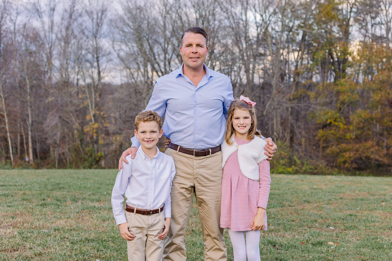 A dad and his two children posing in a field during a family photography session in Burke.