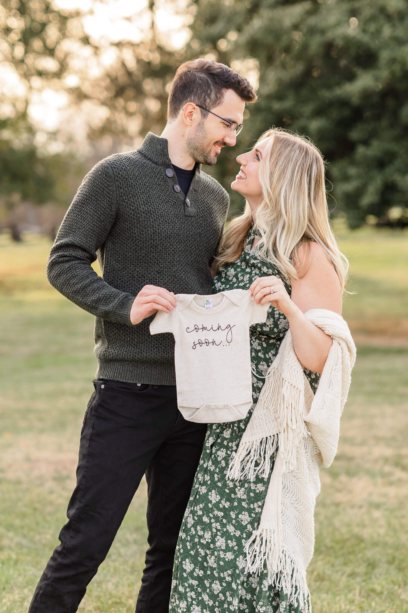 A couple holding a onesie and smiling at each other.