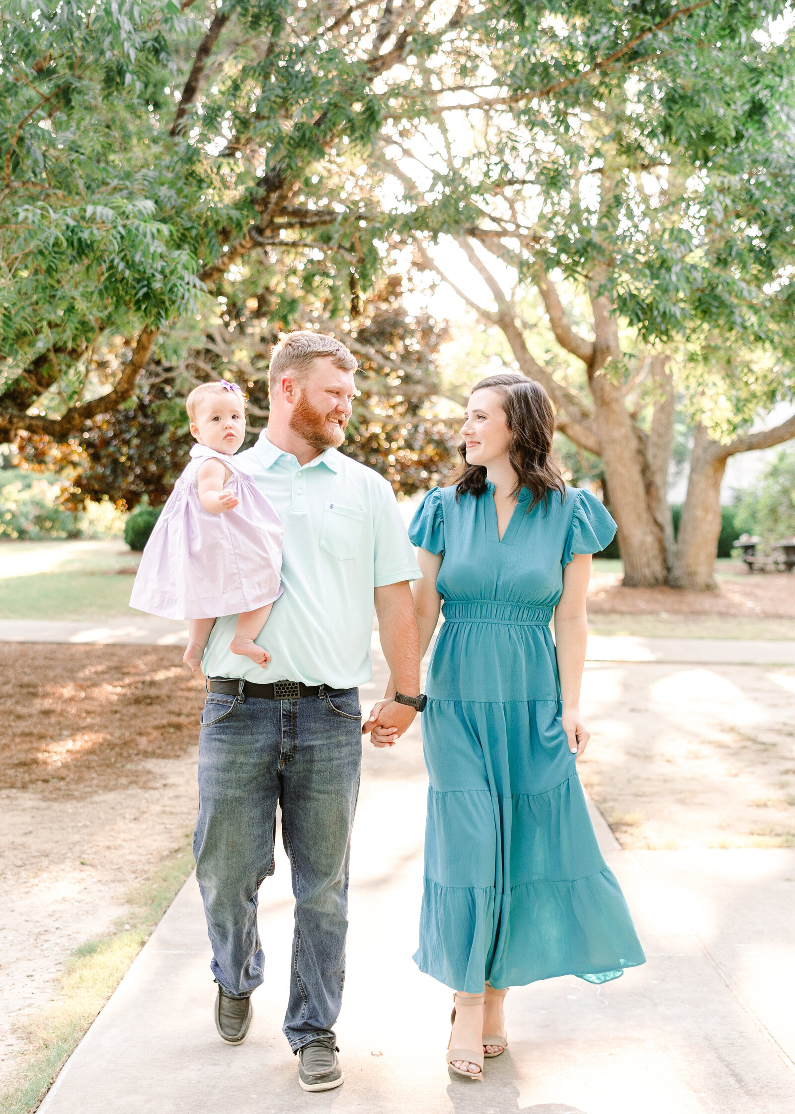 The Wares Family walking hand in hand under lush green trees, captured by Abby Bell Photography, Fine Art Portrait Photographer based in Alabama.