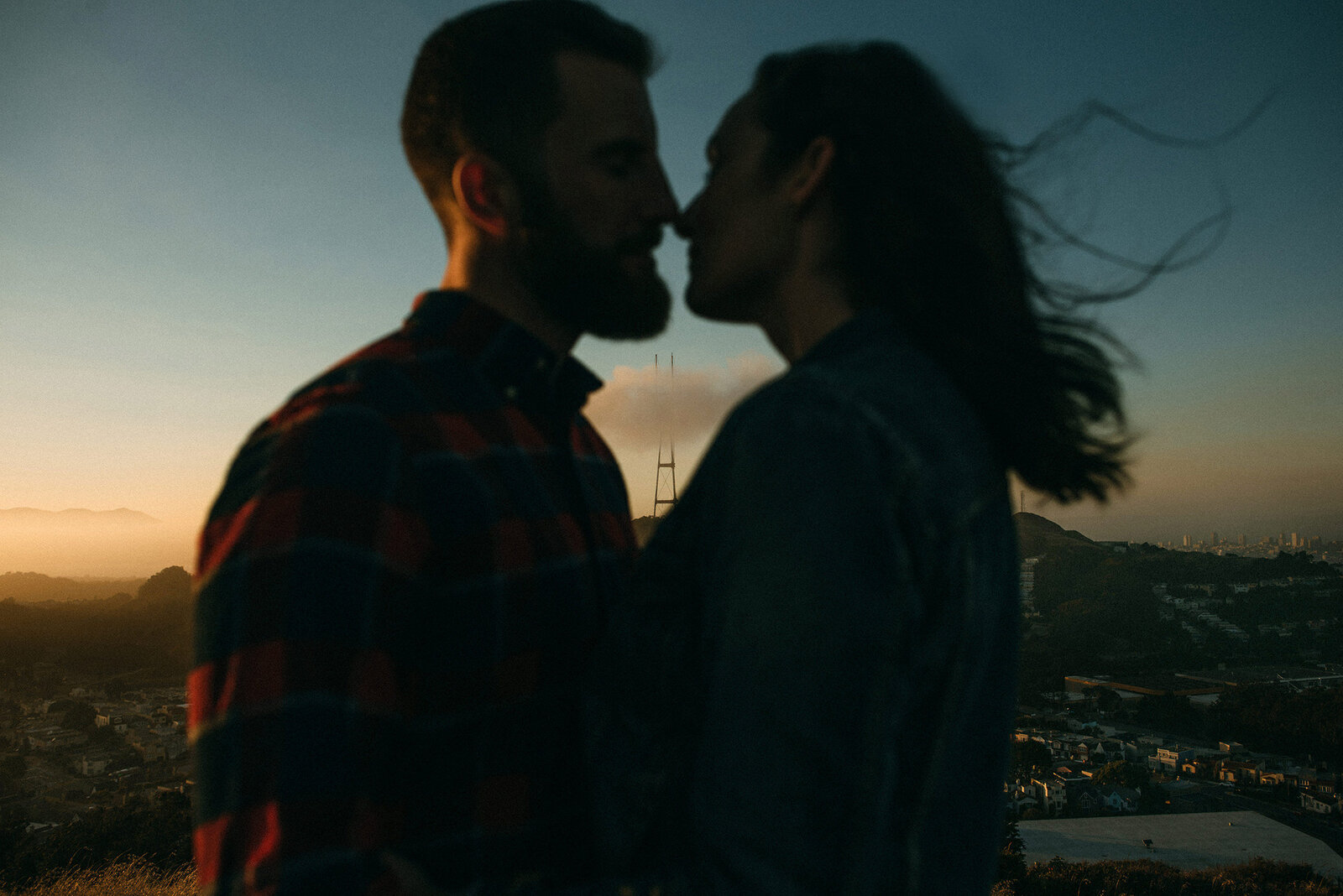 Couple about to kiss for engagement photo with San Francisco background