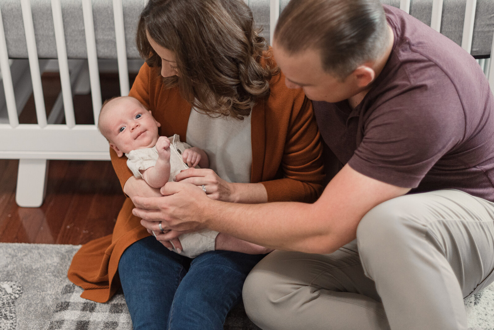 parents sitting on floor in nursery holding baby