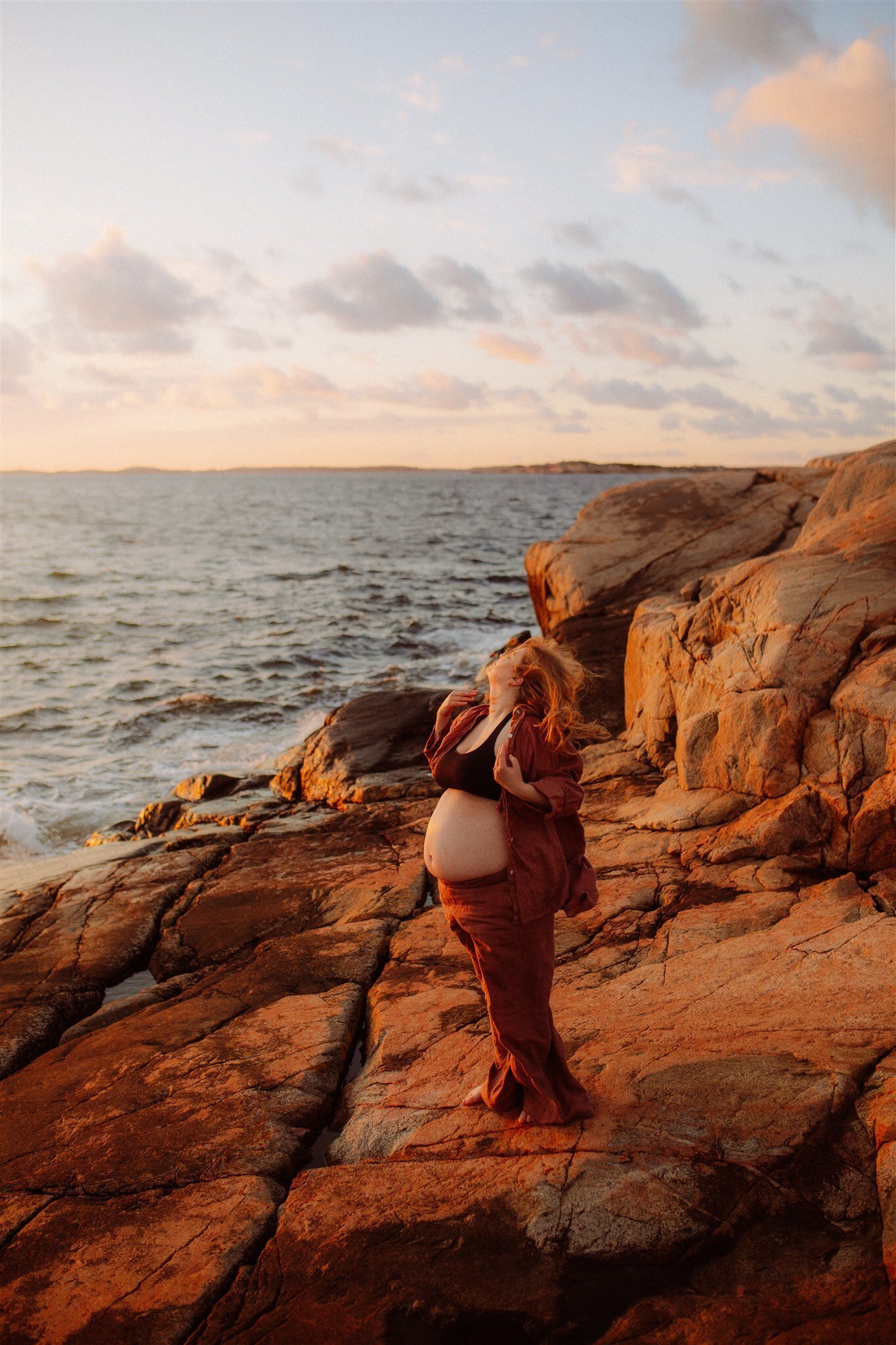 en gravid kvinna sträcker sig mot himlen vid havet
