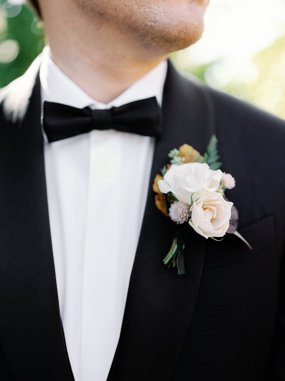 Close up of white boutonniere on black tux.