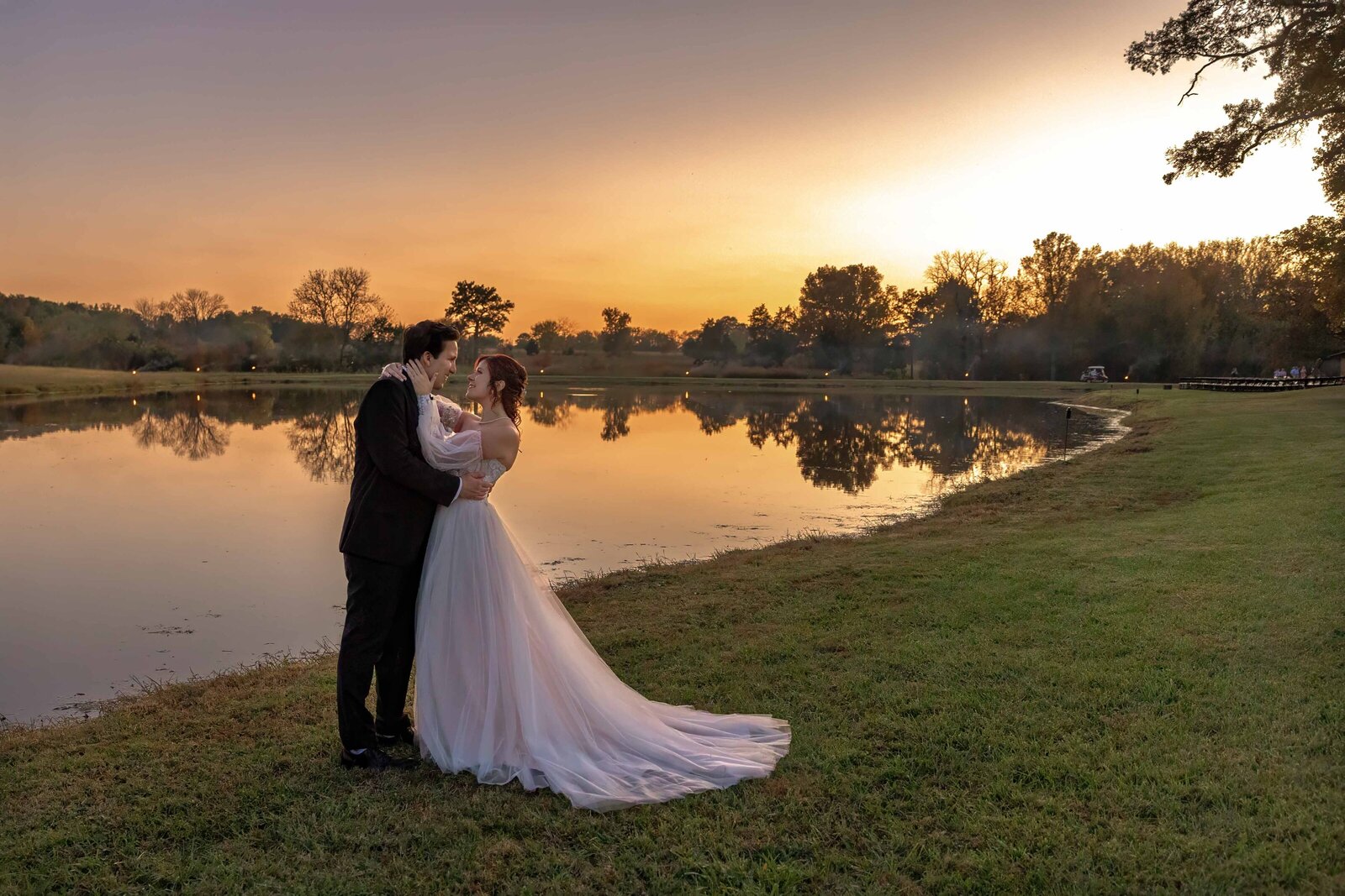 The bride and groom embrace by a reflective pond at sunset, captured during a Boone, NC wedding, blending rustic elegance with natural beauty and golden light.