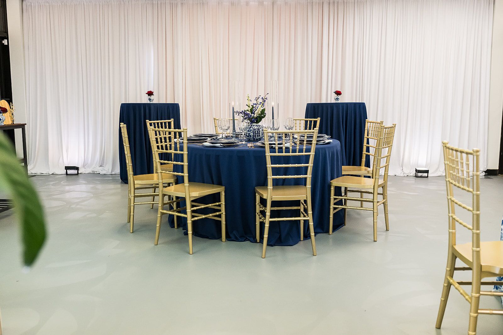 Styled table setup at The Parlor at Wells in Memphis, featuring vibrant floral centerpieces, blue toile linens, gold chairs, and natural light—ideal for showers, workshops, and private dinners.