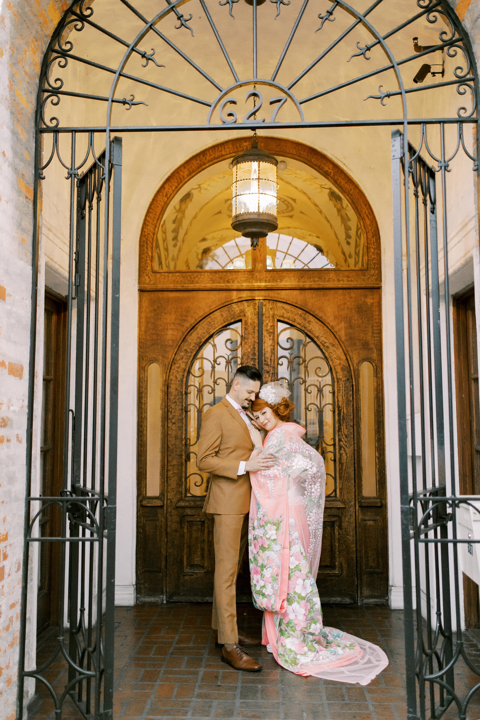 Couple embracing in soft pink iro-uchikake and tan suit at Carondelet House. Wedding kimono rental in Los Angeles | ロサンゼルス カロンデレットハウスで着物レンタル、淡いピンク着物花嫁と新郎が抱き合う