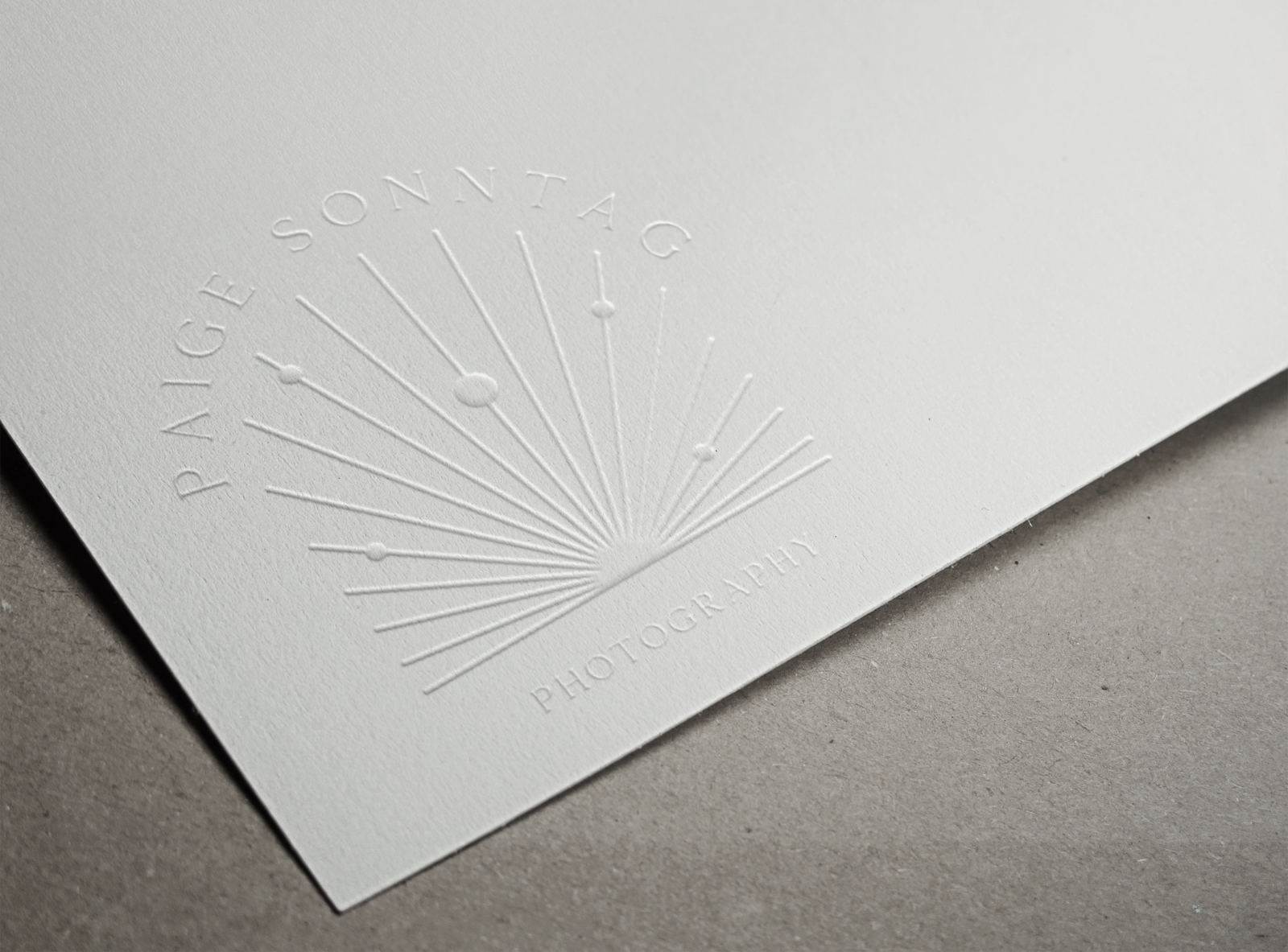 Embossed business card with a radial design and the text "paige sonntag photography.