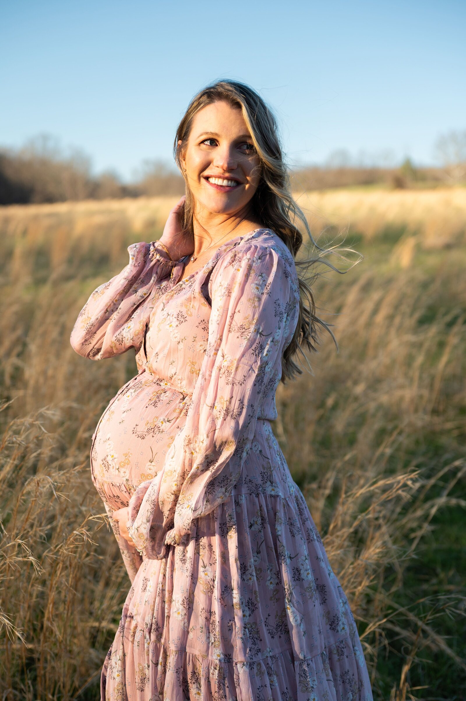 pregnant woman in a field with wind blown hair