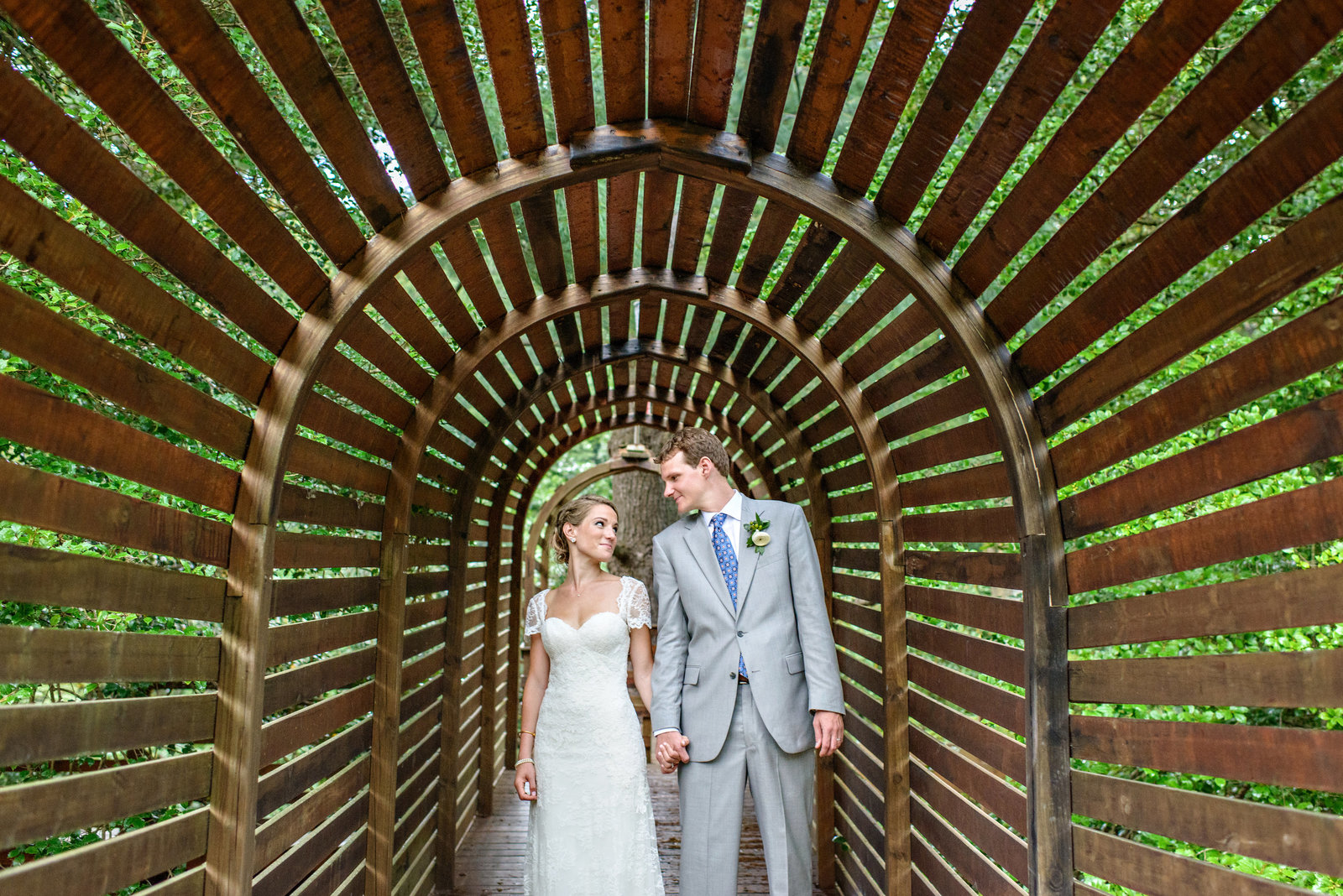 A couple hold hands after their wedding at Tyler Arboretum.