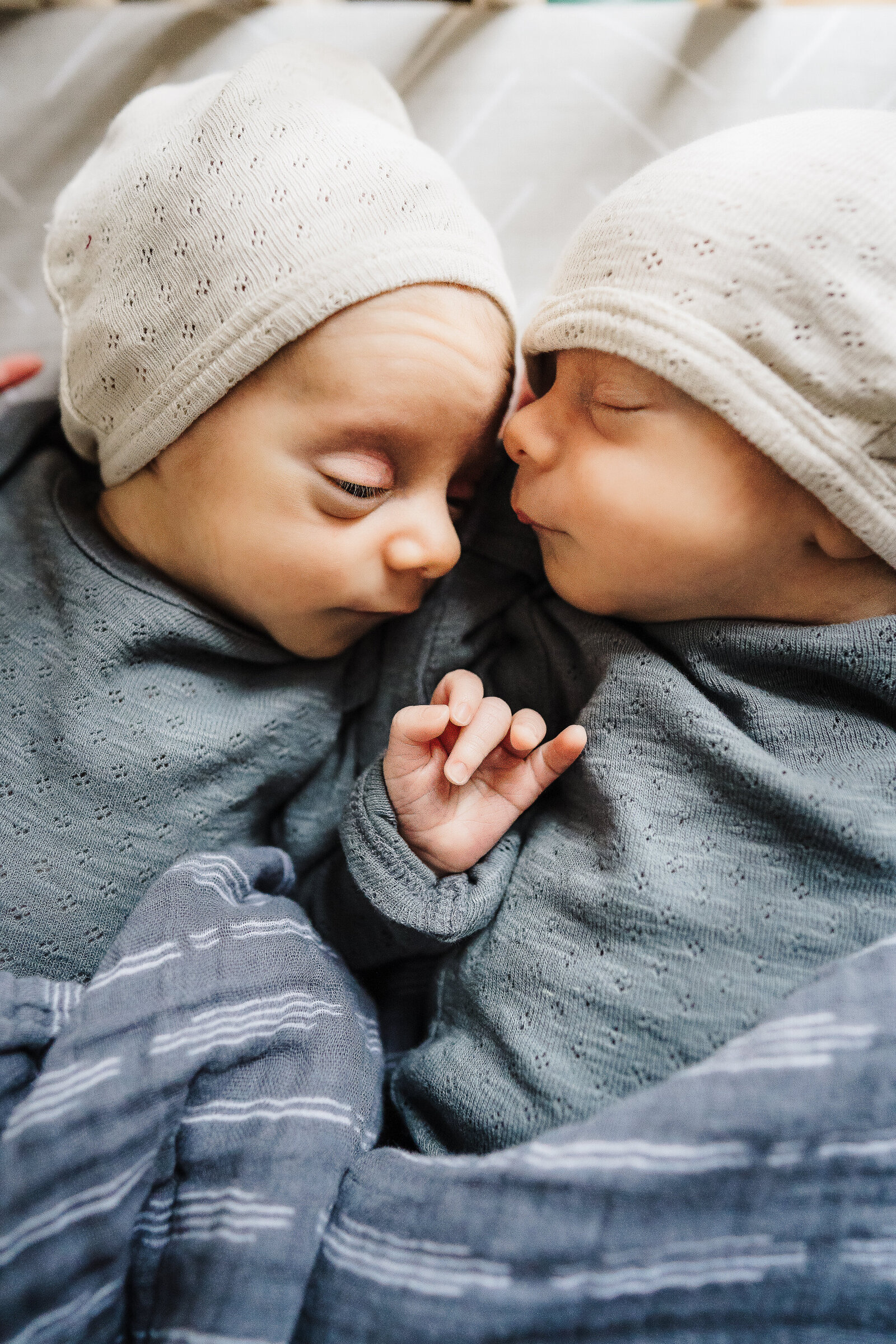 twin baby boys lay nose to nose in crib for newborn pictures in boston