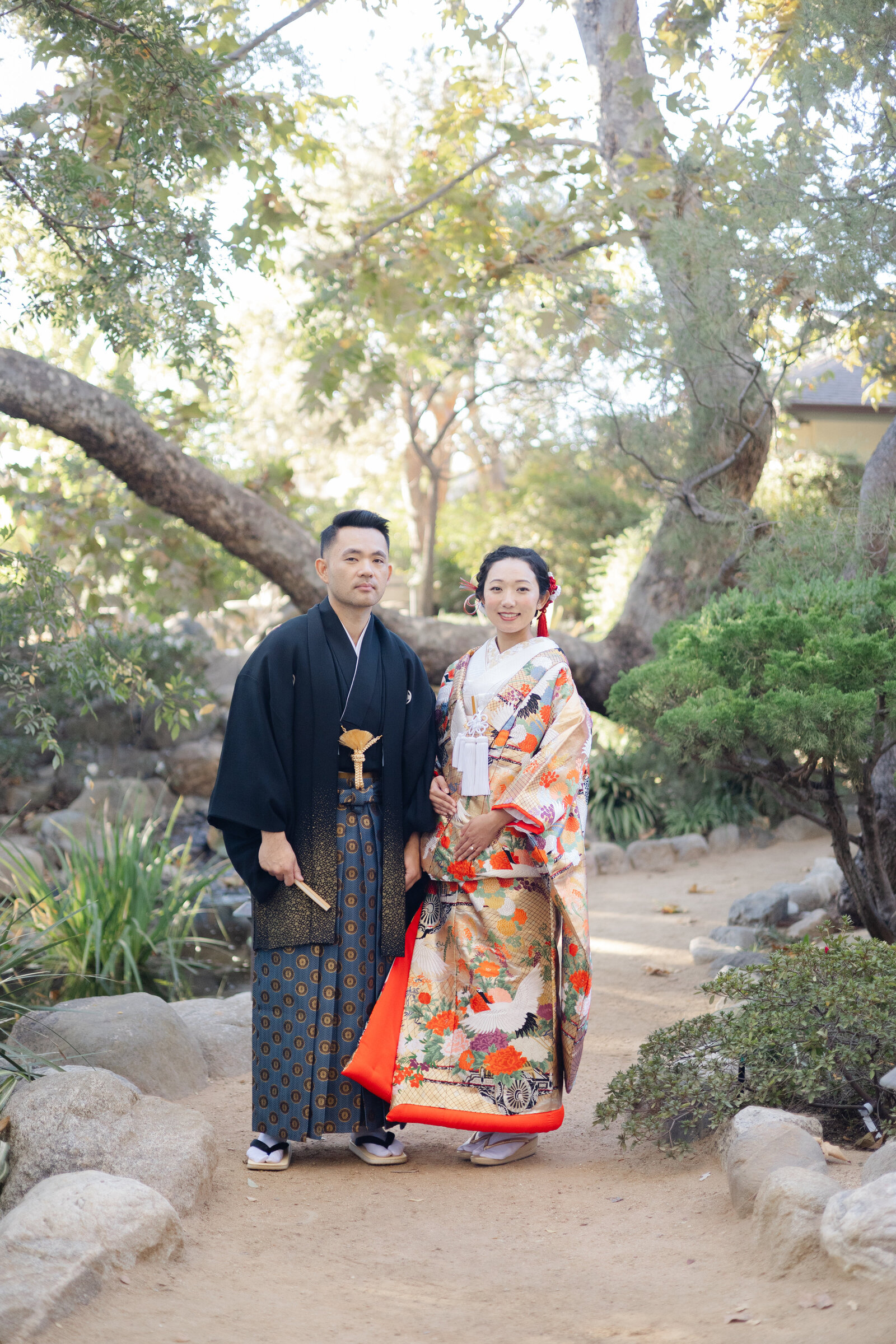 Bride and groom in formal Japanese wedding attire posing along the garden path at Storrier Stearns Japanese Garden, kimono rental in Los Angeles | ロサンゼルスStorrier Stearns Japanese Gardenで和装結婚式姿の新郎新婦が庭園の小道に立つ着物レンタル撮影