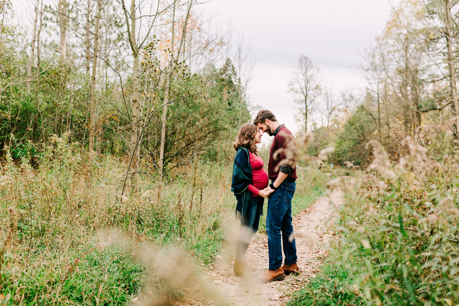 An adorable could hold hands and touch forheads during their maternity session.