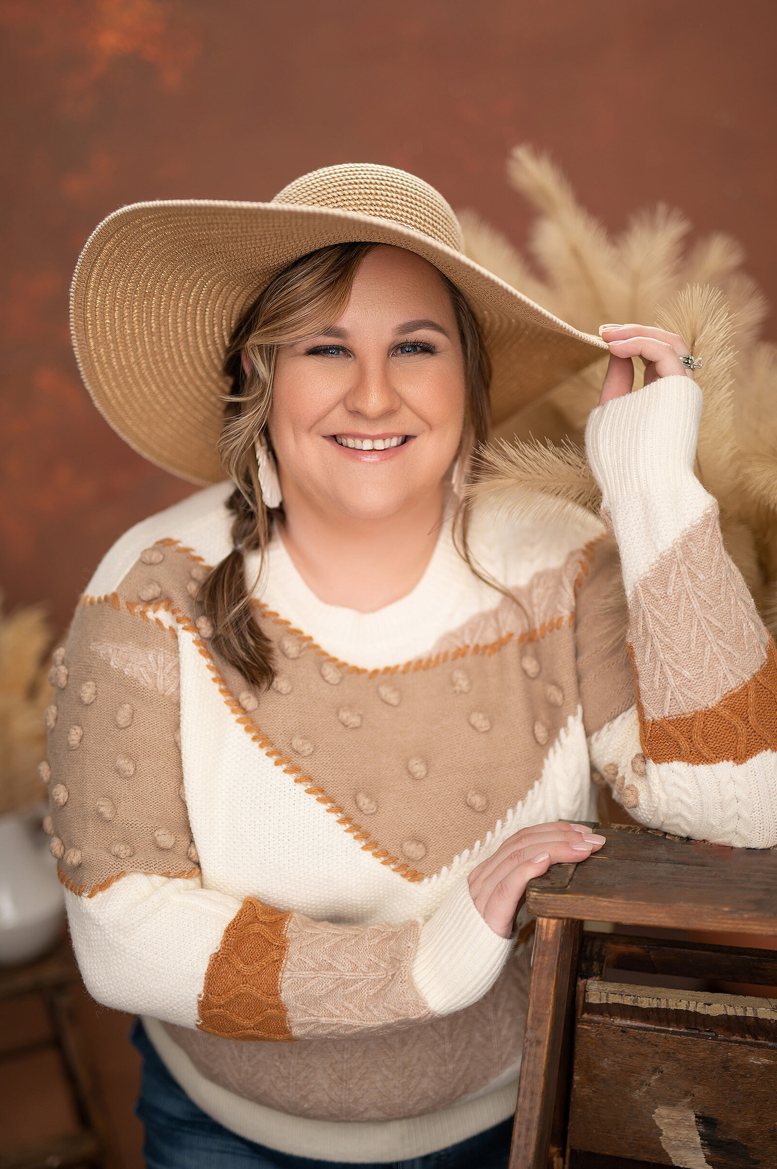 Boho-styled personal branding portrait of a young woman dressed in neutral tones, holding a floppy hat.