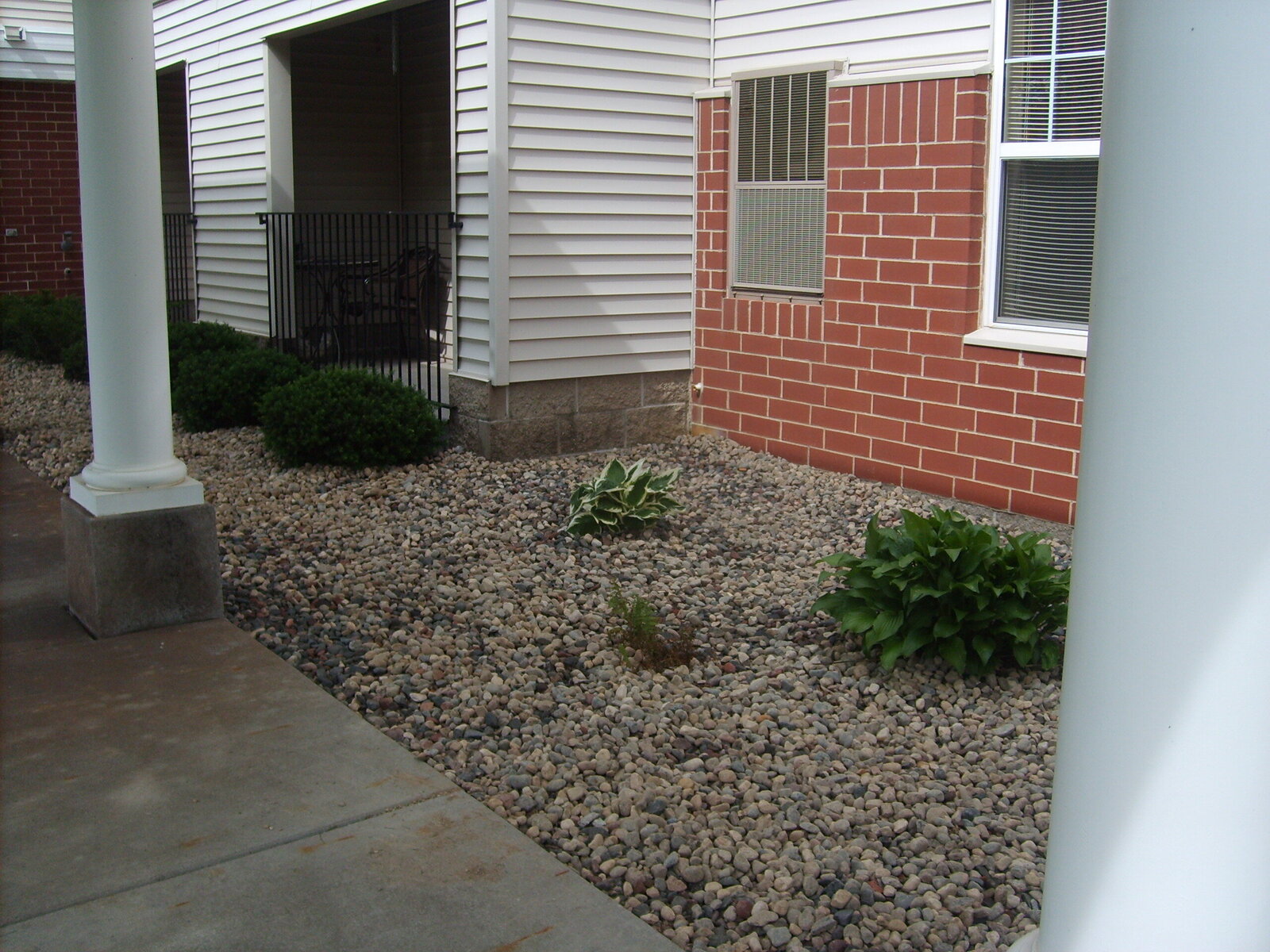 commercial rock beds with shrubs around white appartment building